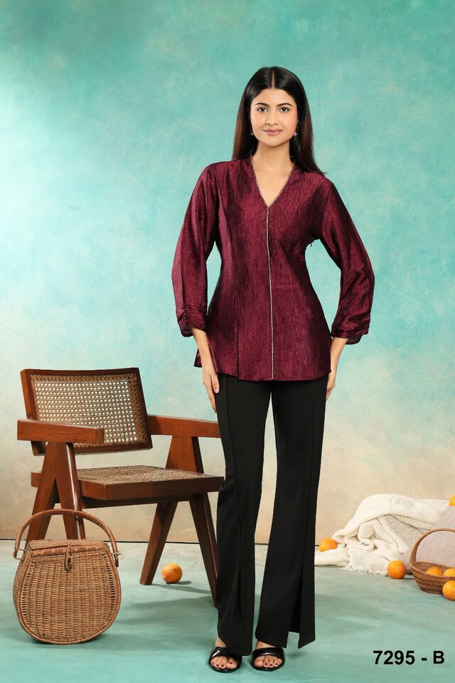 Wine satin peplum blouse with black flared trousers against a teal wall