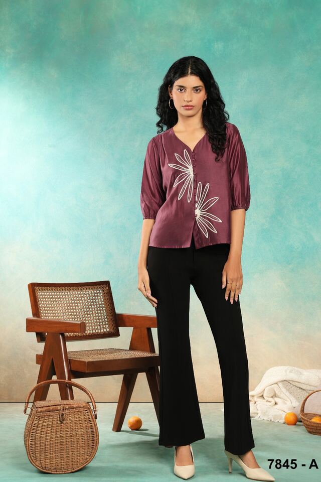 Wine top with a white embroidered spray, worn with black flared trousers